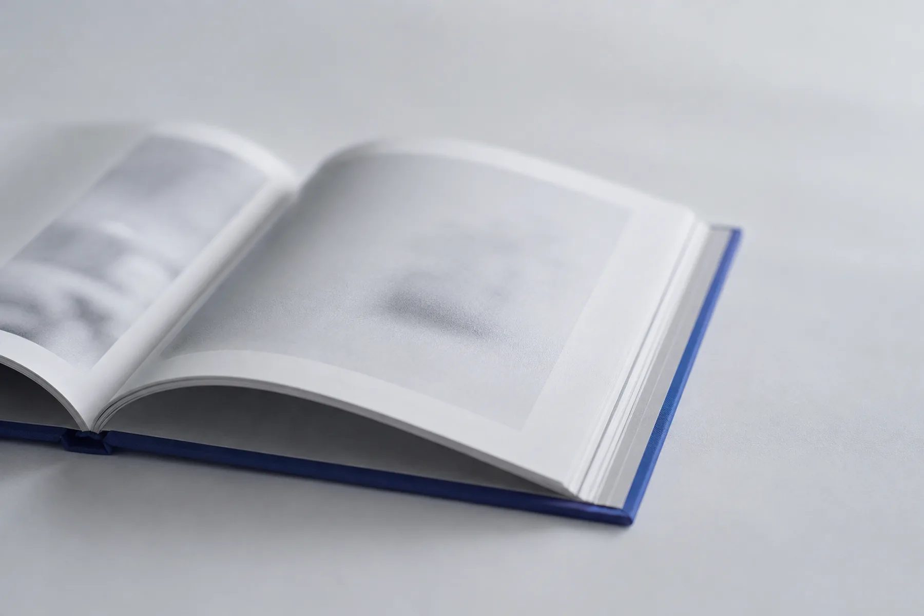 Flach aufgeschlagenes Hardcover-Buch, sichtbarer fadengehefteter Rücken und Licht auf der Seite